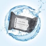 A close-up of a biodegradable makeup wipe removing waterproof mascara from an eye.